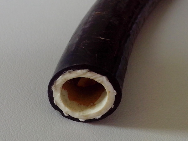 A black fiber reinforced nylon resin hose placed on a flat surface