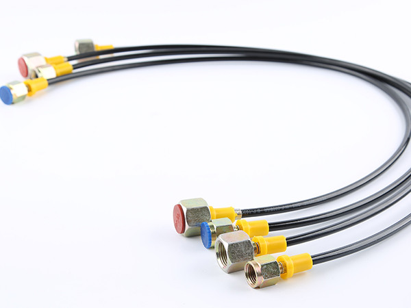Four black fiber reinforced nylon resin hoses placed on a flat surface