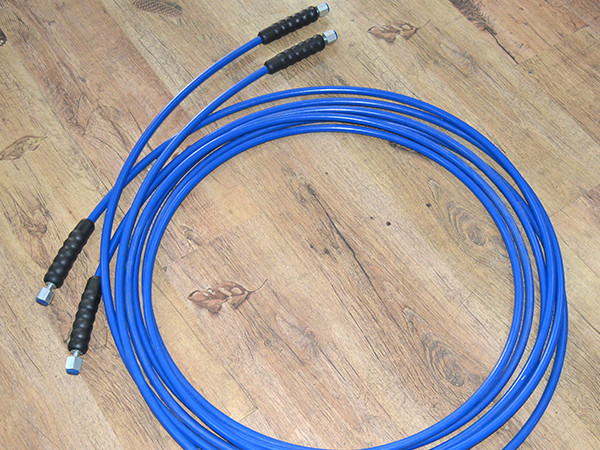 A coil of blue steel wire reinforced nylon resin hose placed on the ground