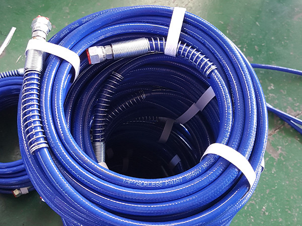 A coil of blue steel wire reinforced nylon resin hose placed on the ground