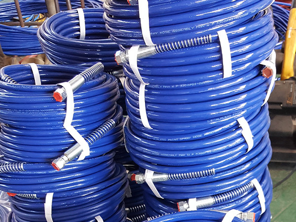 Several coils of blue steel wire reinforced nylon resin hose placed on the ground