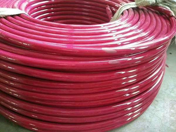 A coil of red steel wire reinforced nylon resin hose placed on the ground